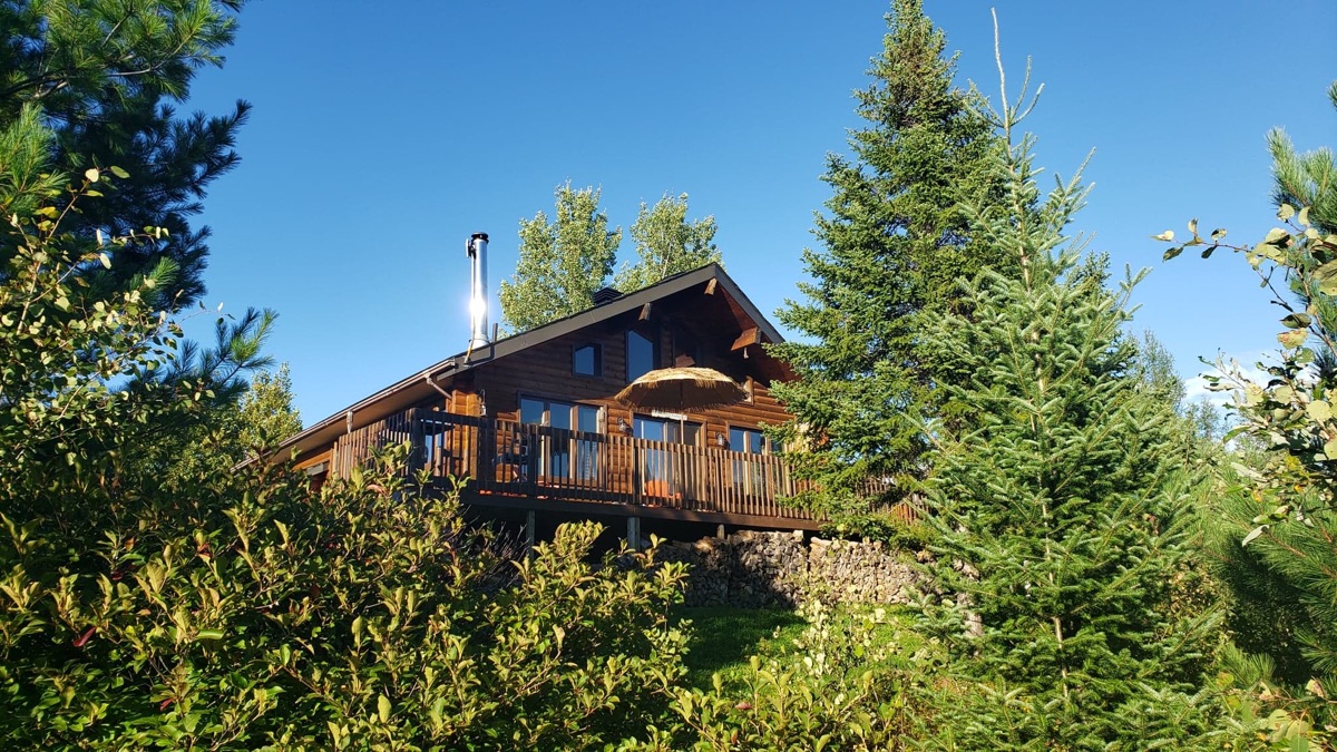 L'Étoile Rouge log cabin among the trees under a blue sky